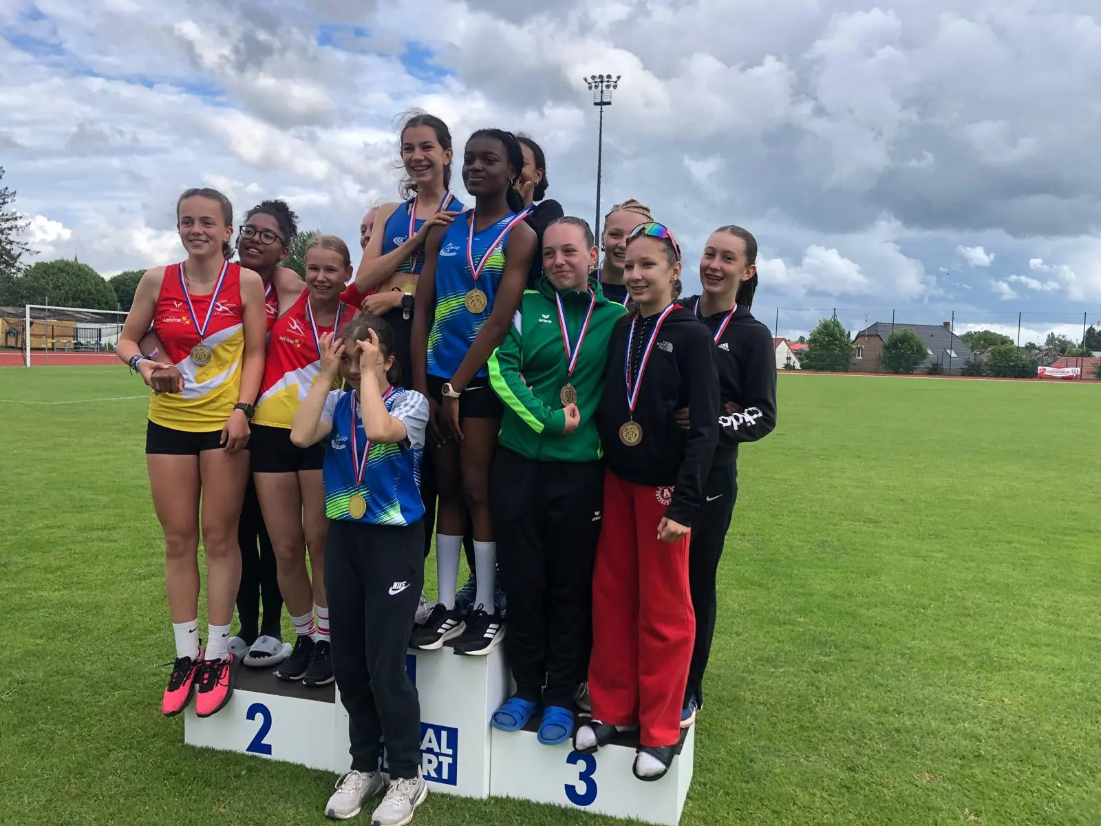 Podium à Caudry : des équipes de jeunes filles médaillées serrées sur le podium, dont une en maillot bleu et vert du club